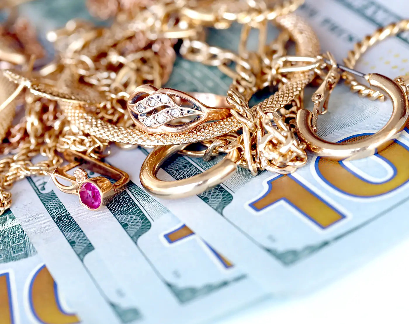 Gold rings, necklaces, and bracelets displayed on money