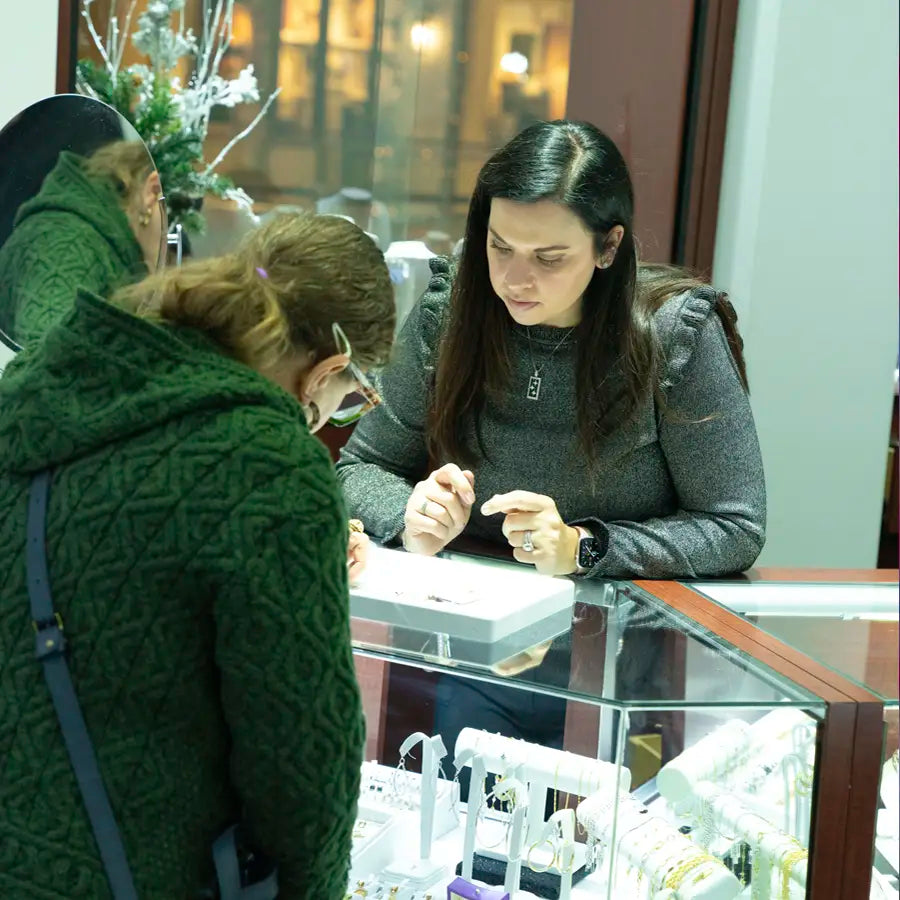 Jeweler showing woman jewelry in display case at Joe Kassab Jewelers in Happy Valley, Oregon